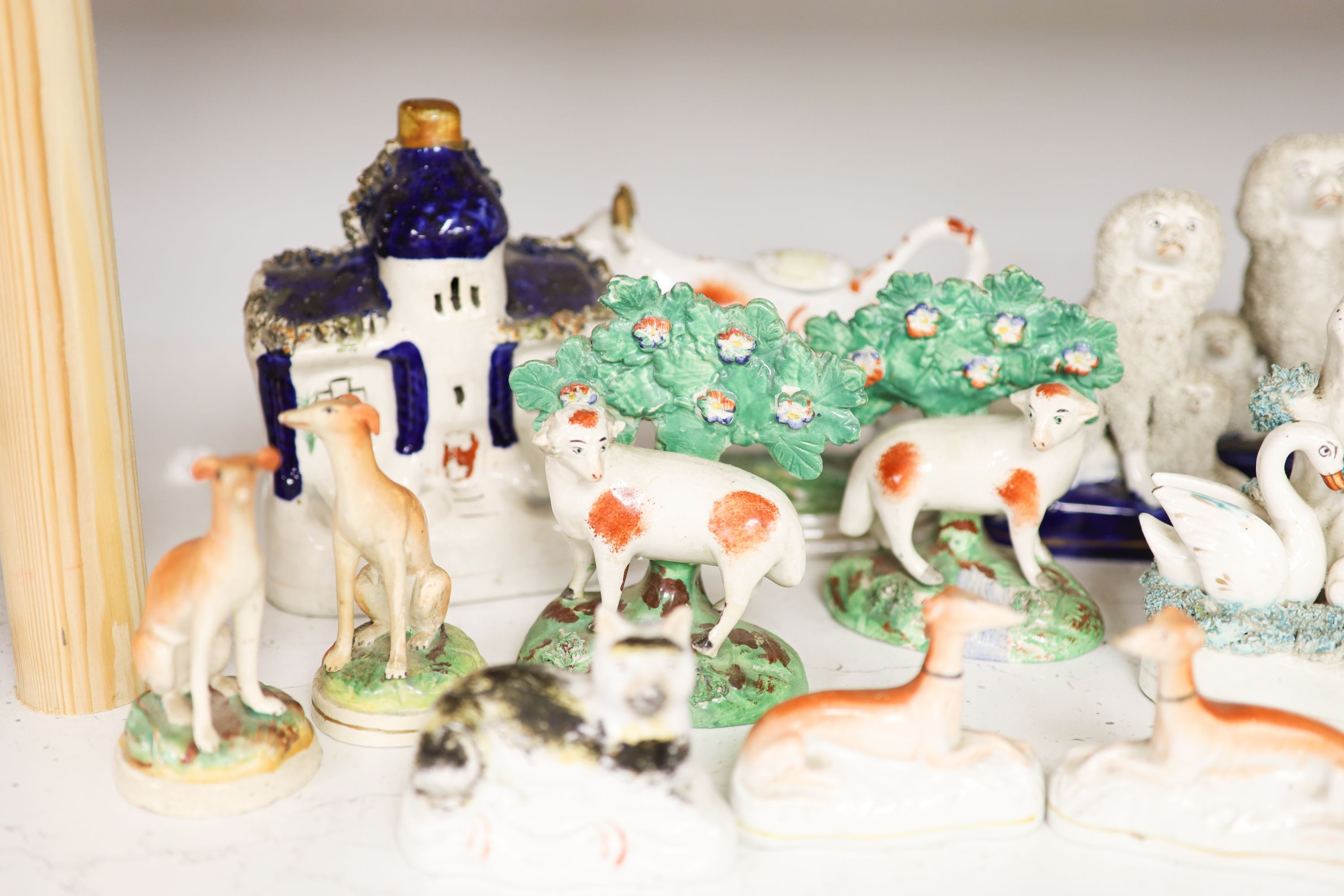 A collection of Victorian Staffordshire pottery to include a sponge glazed seated cat, a pair of bocage sheep, cow creamer etc (14).